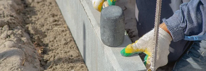 Person setzt Randstein mit Gummihammer